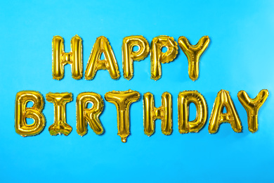 Phrase HAPPY BIRTHDAY made of foil balloon letters on light blue background