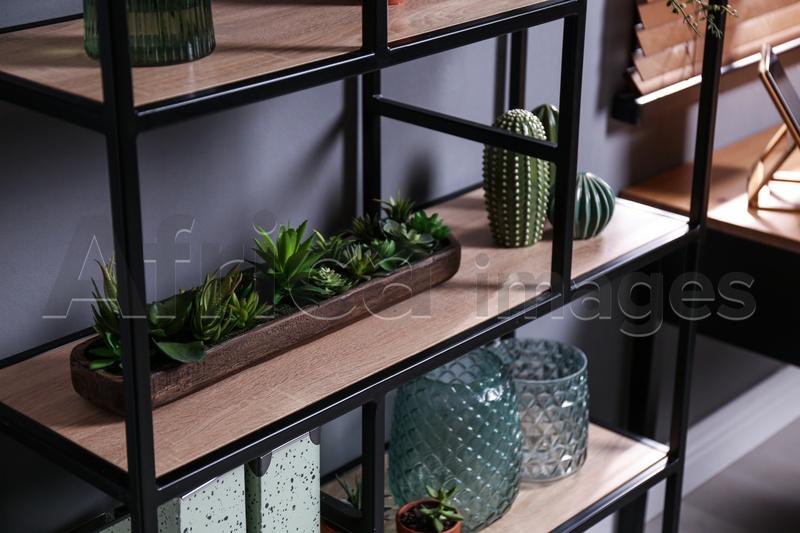 Photo of Shelving with different decor and houseplants near gray wall. Interior design