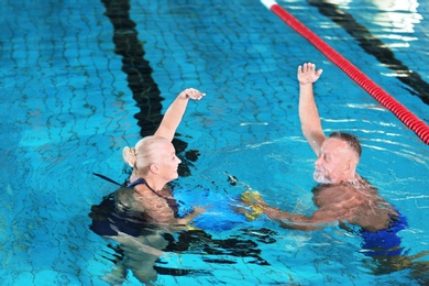 Sportive senior couple doing exercises in indoor swimming pool