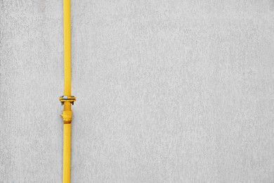 Photo of Yellow gas pipe near beige wall outdoors, space for text