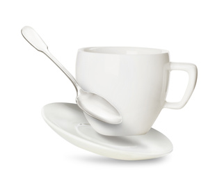 Clean cup with saucer and teaspoon in flight on white background