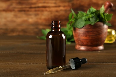 Glass bottle and pipette with nettle oil on wooden table