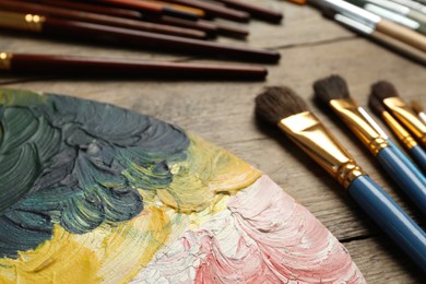 Brushes and palette on wooden table, closeup