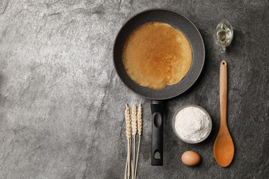 Frying pan with delicious crepe, spikelets and ingredients on grey table, flat lay. Space for text