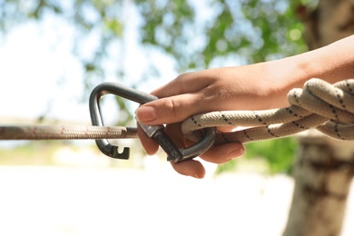 Woman using screw lock carabiner during training outdoors, closeup
