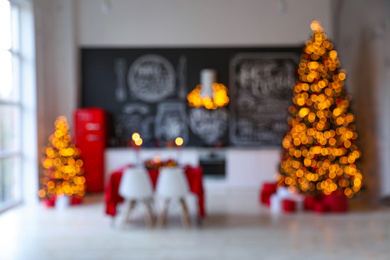 Stylish kitchen interior with festive table and  decorated Christmas trees, blurred view