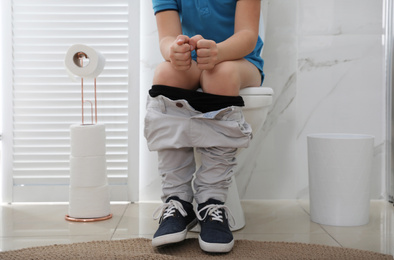 Boy suffering from hemorrhoid on toilet bowl in rest room, closeup