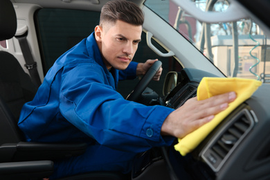 Car wash worker cleaning modern automobile interior