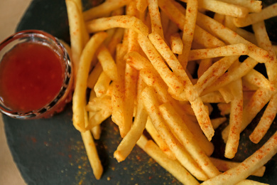 Above view of delicious hot french fries with red sauce served on table, closeup