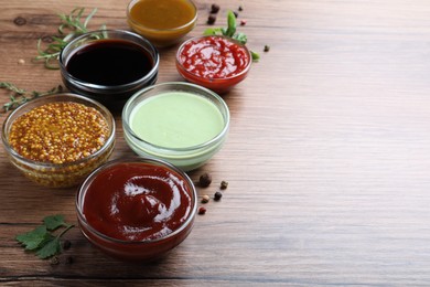 Photo of Many different sauces on wooden table, space for text