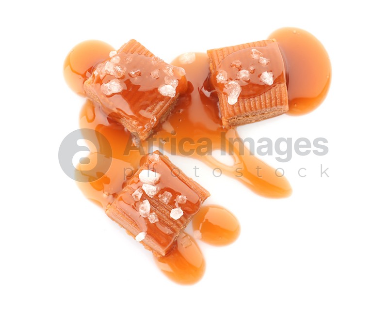 Delicious candies with caramel sauce and salt on white background