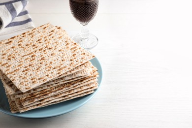 Stack of matzos and red wine on white table. Space for text