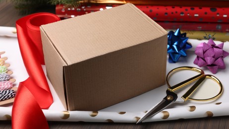 Box, wrapping paper and scissors on wooden table, closeup