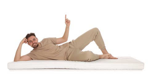 Photo of Man lying on soft mattress and pointing upwards against white background