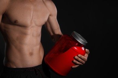 Athletic man with big red jar on black background, closeup. Doping concept