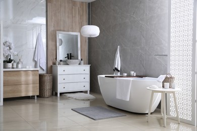 Modern white tub and chest of drawers with sink in bathroom. Interior design