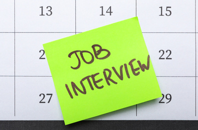 Reminder note about job interview on calendar, top view