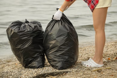 Woman with trash bags full of garbage on beach, closeup