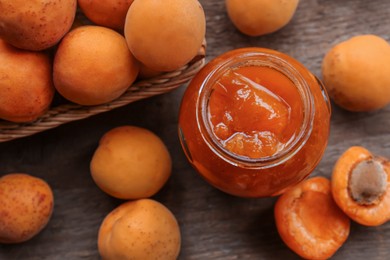 Jar of delicious jam and fresh ripe apricots on wooden table, flat lay. Fruit preserve