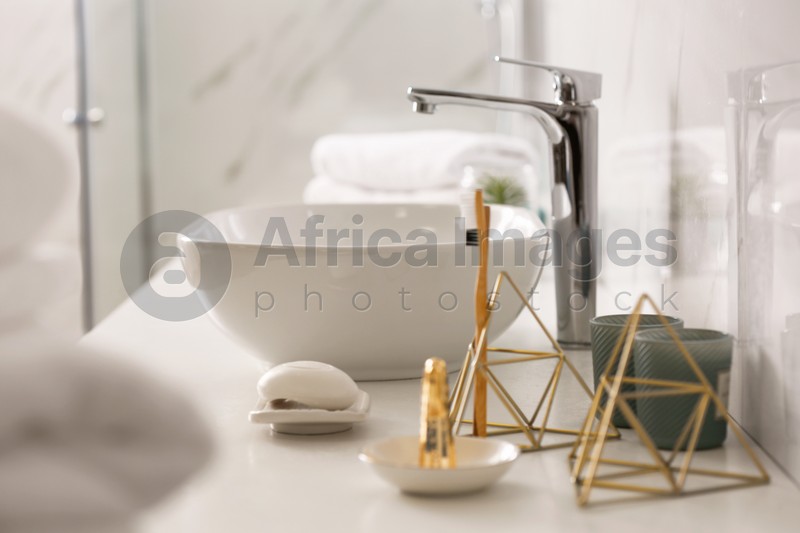 Photo of Toiletries and vessel sink on light countertop in modern bathroom