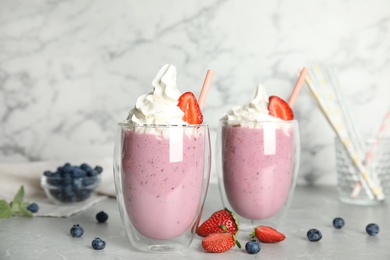 Tasty milk shakes with fresh berries on grey marble table