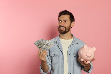 Photo of Happy man with money and piggy bank on pale pink background