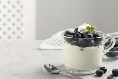 Delicious yogurt with blueberries served on grey marble table, space for text