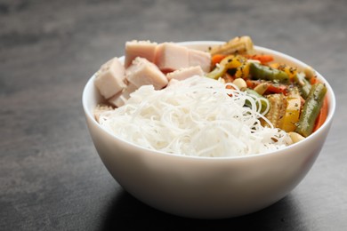 Photo of Tasty cooked rice noodles with chicken and vegetables on grey table