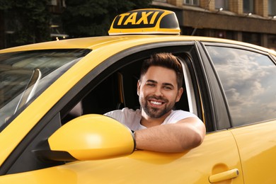 Photo of Handsome taxi driver in car on city street