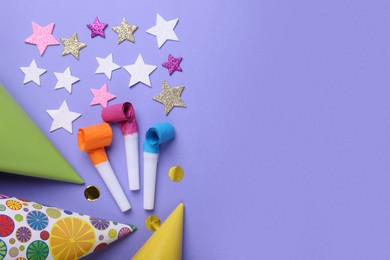 Photo of Party hats, blowers and confetti for birthday party on violet background, flat lay. Space for text