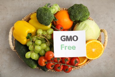 Tasty fresh GMO free products and paper card on light grey table, top view