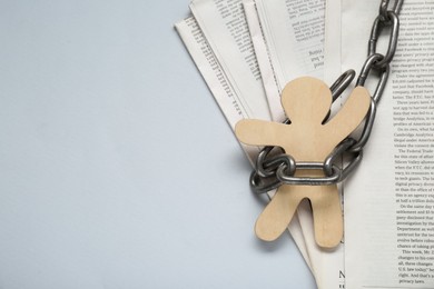 Photo of Information warfare concept. Chained wooden figure and newspapers on light grey background, top view with space for text
