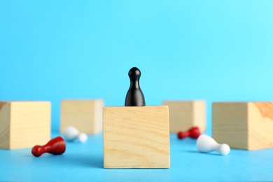 Board game pawn on top of wooden cube with other ones fallen against color background