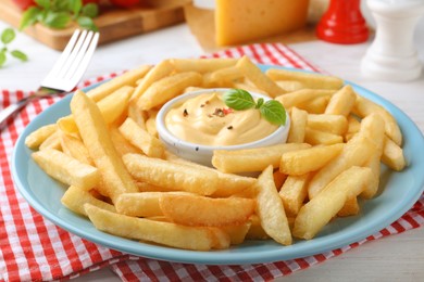 Delicious French fries and cheese sauce with basil on white table, closeup