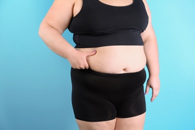 Photo of Overweight woman touching belly fat before weight loss on color background