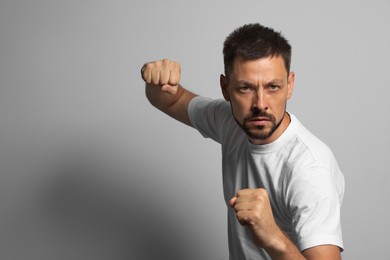 Man ready to fight on grey background, space for text