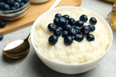 Delicious rice pudding with blueberries on marble table, closeup