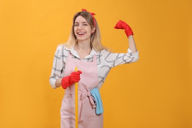 Young housewife with broom on yellow background