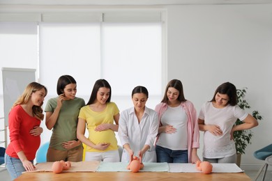 Pregnant women learning how to swaddle baby at courses for expectant mothers indoors