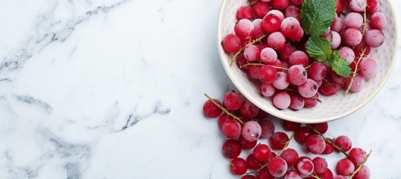 Tasty frozen red currants on white marble table, flat lay. Space for text