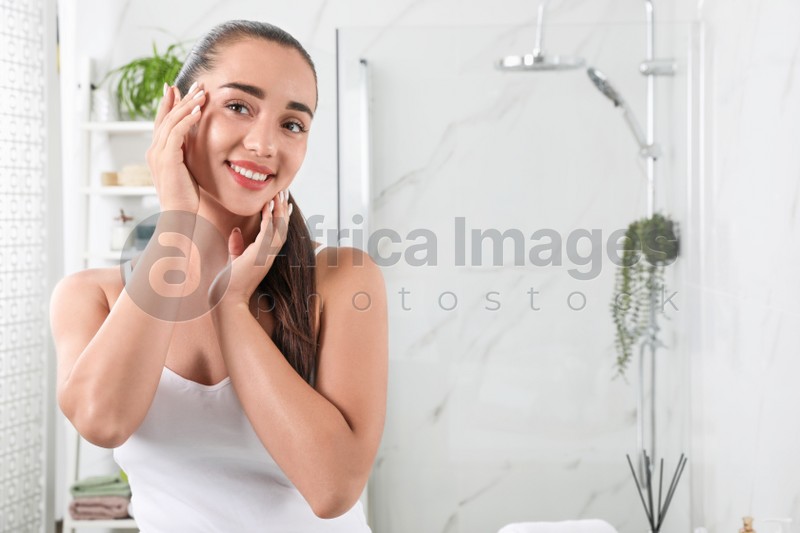 Beautiful young woman with perfect skin in bathroom, space for text. Facial wash