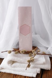 Scented sachet, pussy willow branches and towel on wooden table