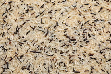 Mix of different brown and polished rice as background, top view
