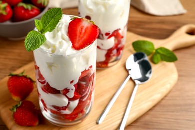 Delicious strawberries with whipped cream served on wooden table, closeup. Space for text