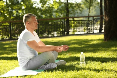 Image of Mature man practicing yoga in green park