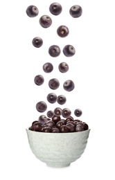 Fresh acai berries falling into bowl on white background