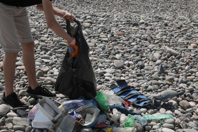 Photo of Man with trash bag collecting garbage in nature, closeup. Environmental Pollution concept