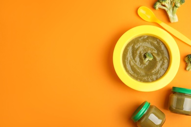 Flat lay composition with healthy baby food and broccoli on orange background. Space for text