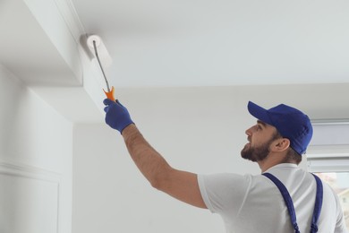 Handyman painting ceiling with white dye indoors
