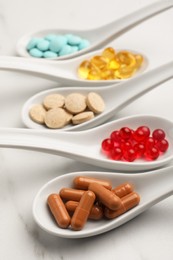 Spoons with different dietary supplements on white table